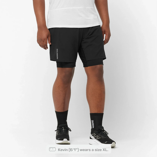Person wearing black athletic shorts with a white background