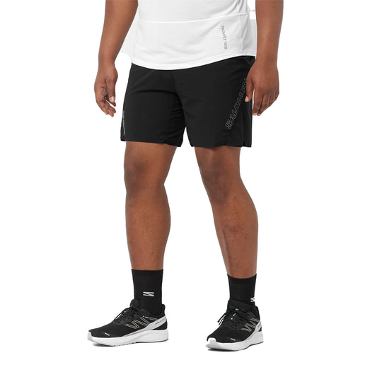 Person wearing black athletic shorts and black sneakers on a white background