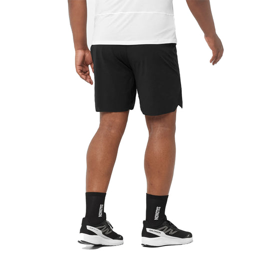 Person wearing black athletic shorts, black socks, and black athletic shoes on a white background
