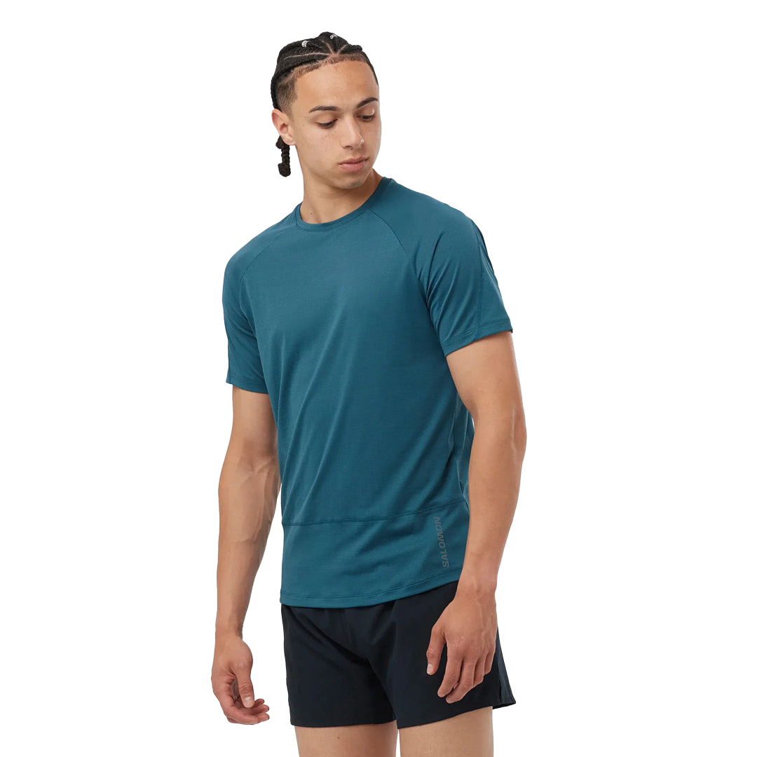 Man wearing a teal athletic shirt and black shorts on a white background
