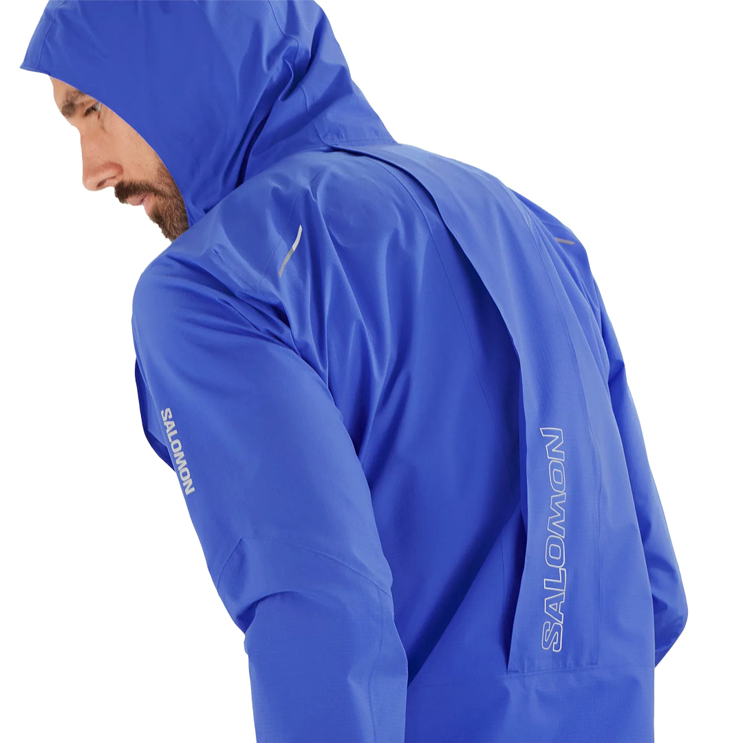 Person wearing a blue Salomon raincoat on a white background