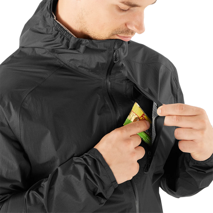 Person wearing a black jacket with a pocket, opening it to reveal a snack.
