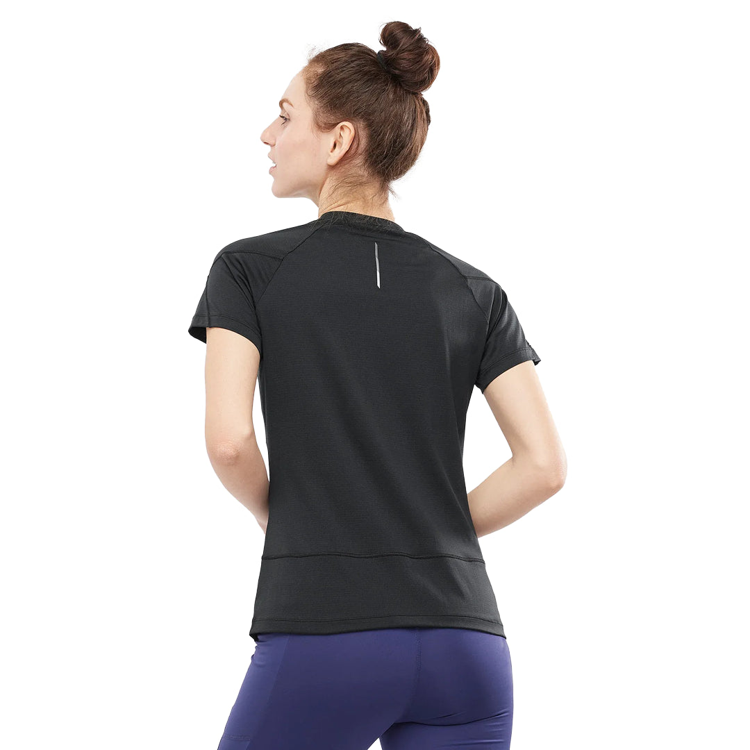 Woman wearing a black athletic shirt and purple leggings on a white background
